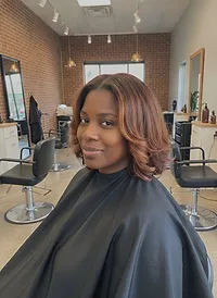 A smiling client with shoulder-length copper-brown hair in soft waves