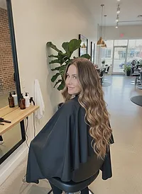 A client glancing over her shoulder, long dark-blonde hair in loose waves