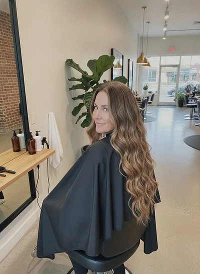 A client glancing over her shoulder, long dark-blonde hair in loose waves