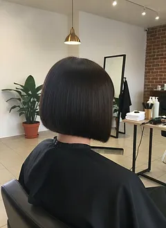 Shoulder-length layered hair with a rich glossy chestnut finish after a gloss treatment, seen in profile