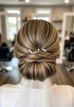 A polished bridal low chignon with pearl pins set into the twist