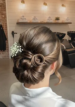 A soft textured wedding updo of pinned curls with small white flowers