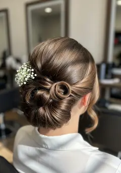 A soft textured wedding updo of pinned curls with small white flowers